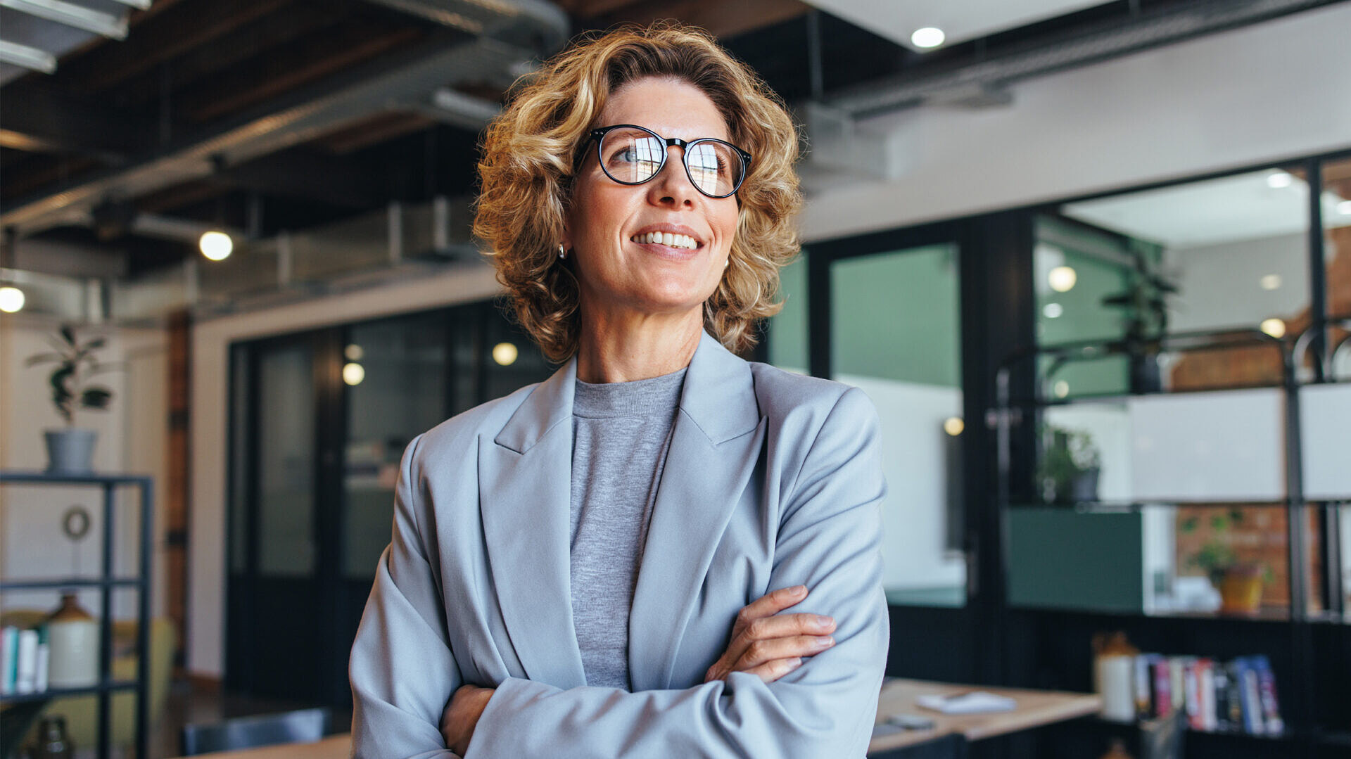 Mulher profissional no escritório, tranquila e sorridente, por ter um seguro de responsabilidade civil profissional