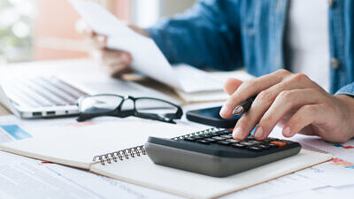 Homem usando calculadora e conferindo documentos