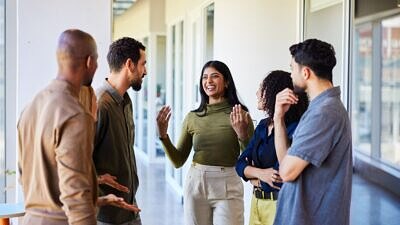 Mulher jovem rindo conversando com colegas em um corredor de escritório