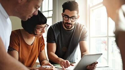 grupo de quatro pessoas ao redor de uma mesa com um notebook