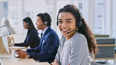 Mulher sorrindo e uma equipe trabalhando no call center