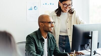 Um homem e uma mulher olhando a tela de um computaodr