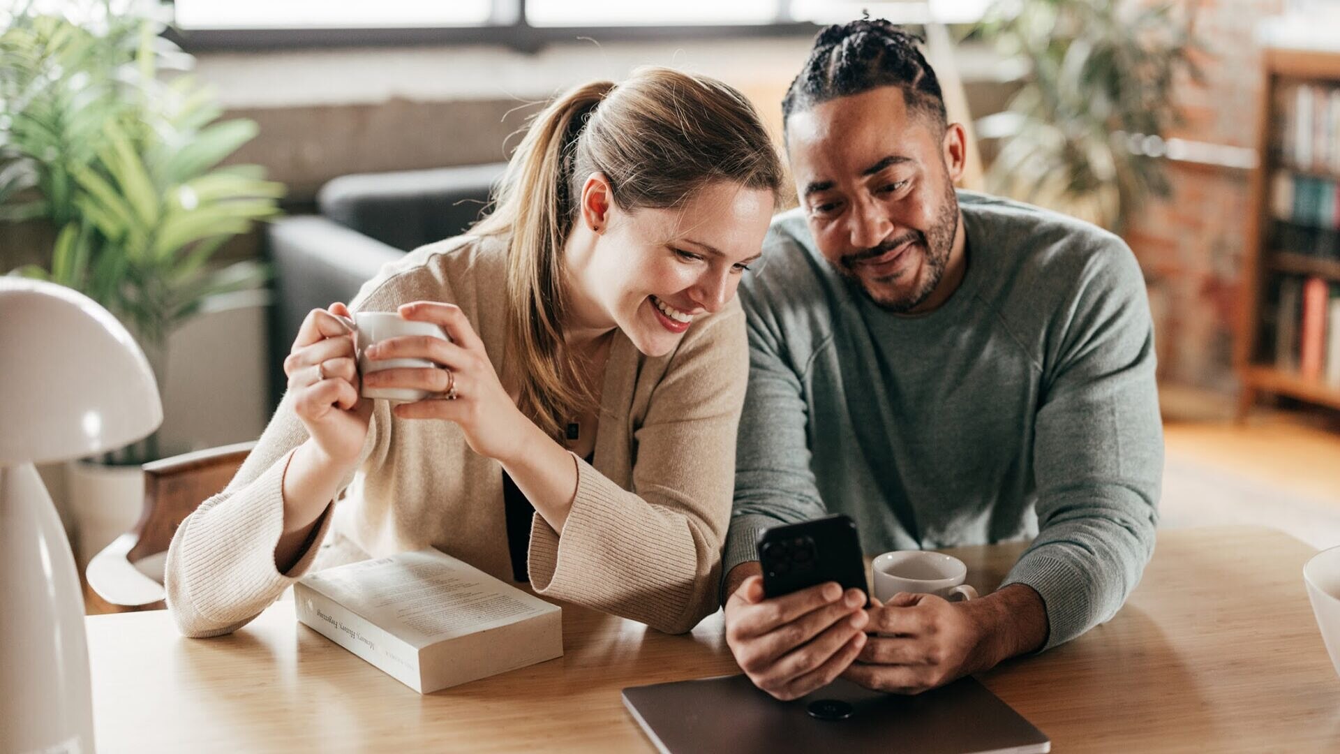 Uma mulher e um homem olhando o celular na mesa