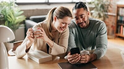Uma mulher e um homem olhando o celular na mesa
