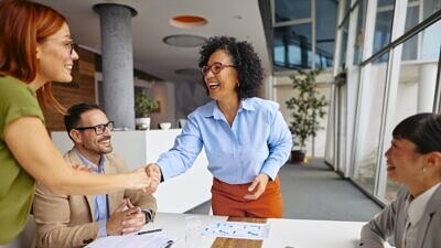 Uma mulher cumprimentando a equipe na mesa